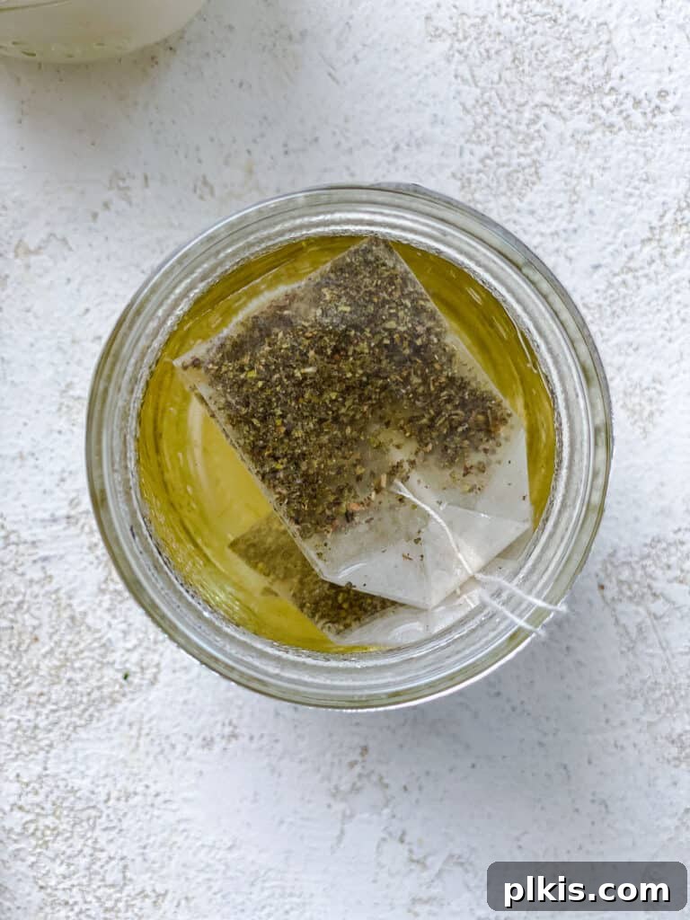 Tropical Mango Bubble 5 Green tea bags steeping in a clear glass of hot water, emitting a gentle steam, indicating the brewing process.