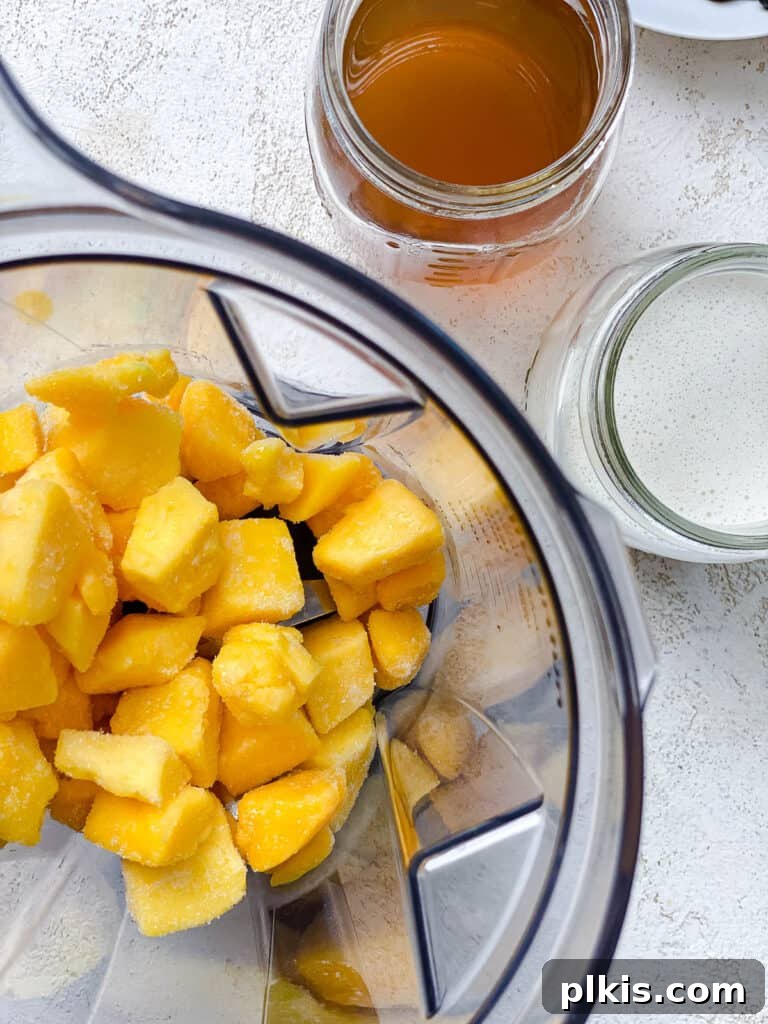 Tropical Mango Bubble 6 Bright orange mango cubes being added into a blender, showcasing the fresh, ripe fruit ready for blending with other ingredients.