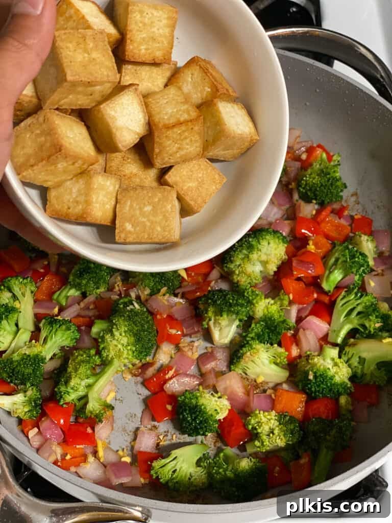 Speedy Teriyaki Tofu Bowl 5 Process shot of adding cooked tofu back into a pan with sautéed vegetables