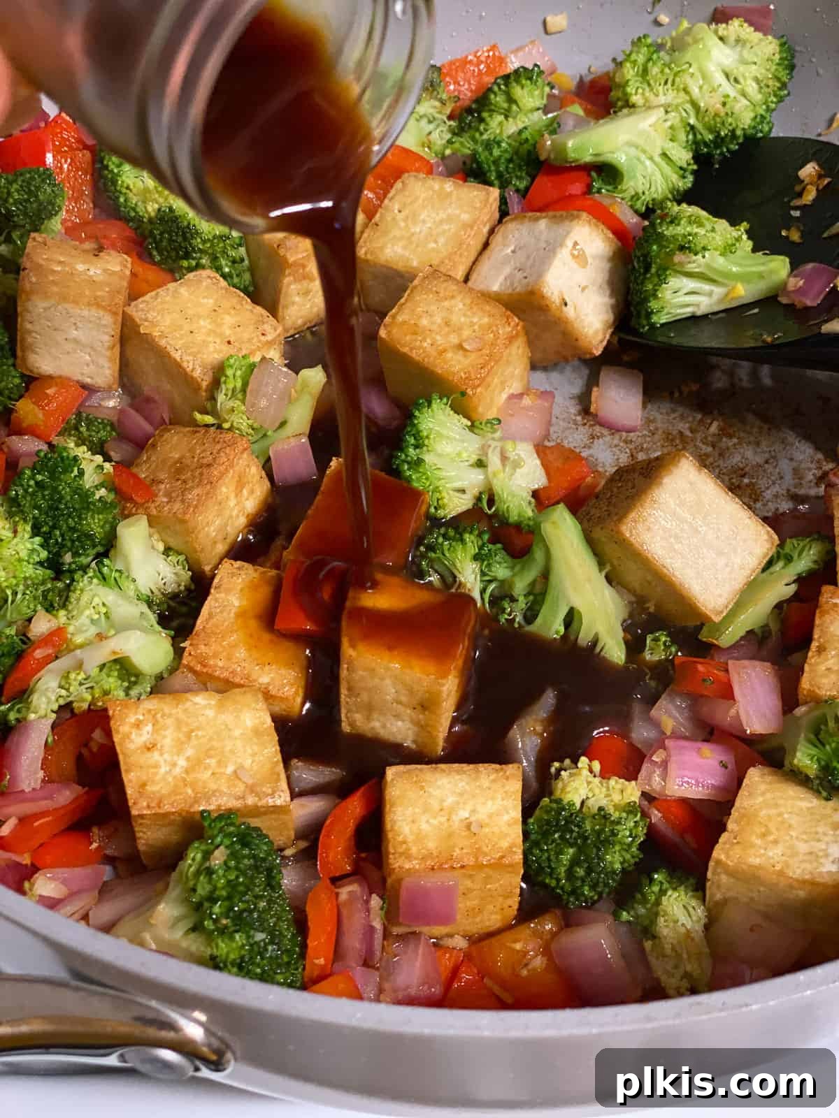 Speedy Teriyaki Tofu Bowl 6 Process shot of pouring teriyaki sauce into a pan of cooked tofu and mixed vegetables