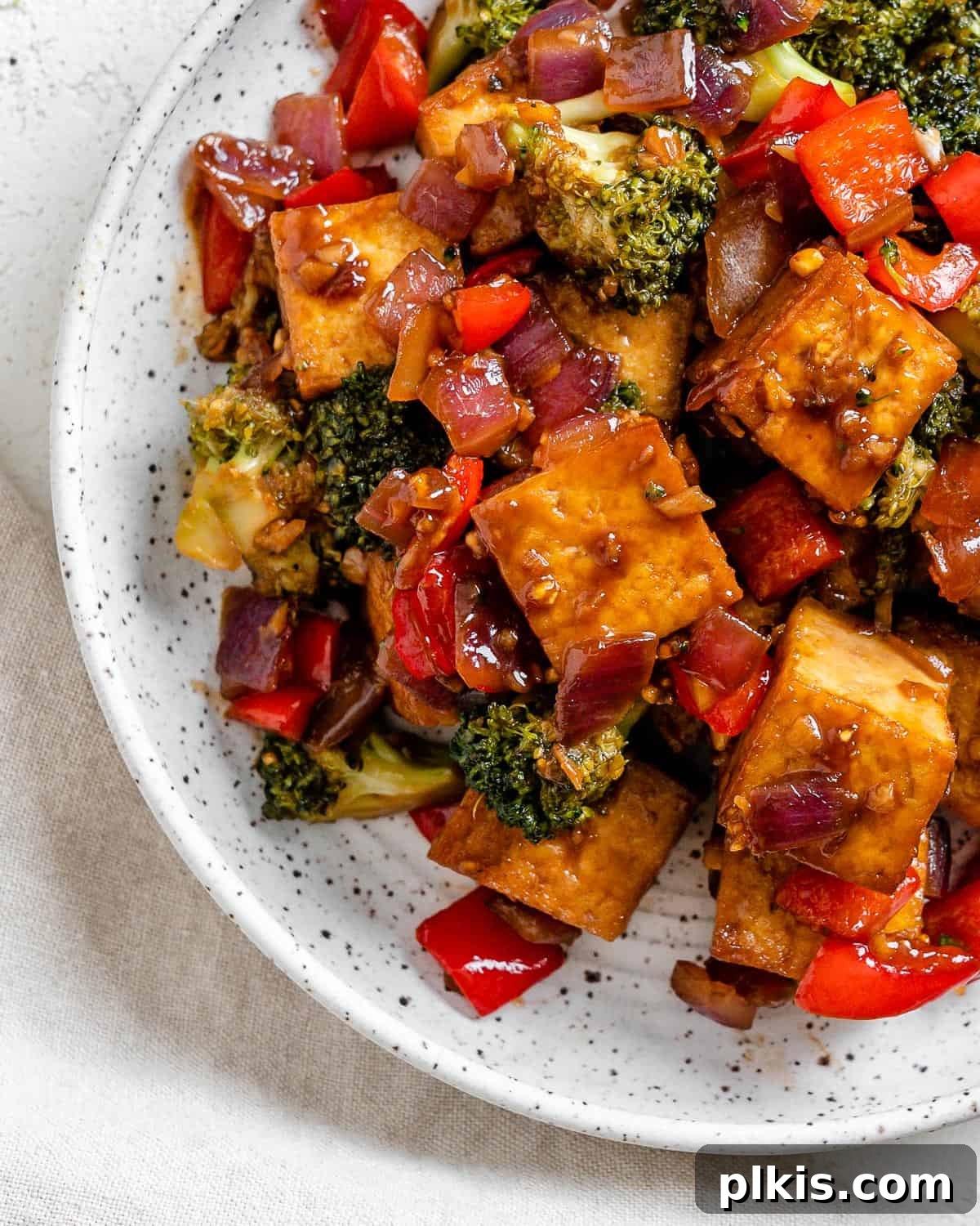 Speedy Teriyaki Tofu Bowl 7 Completed Vegan Teriyaki Tofu Stir Fry plated on a white bowl against a light surface with a sprinkle of sesame seeds