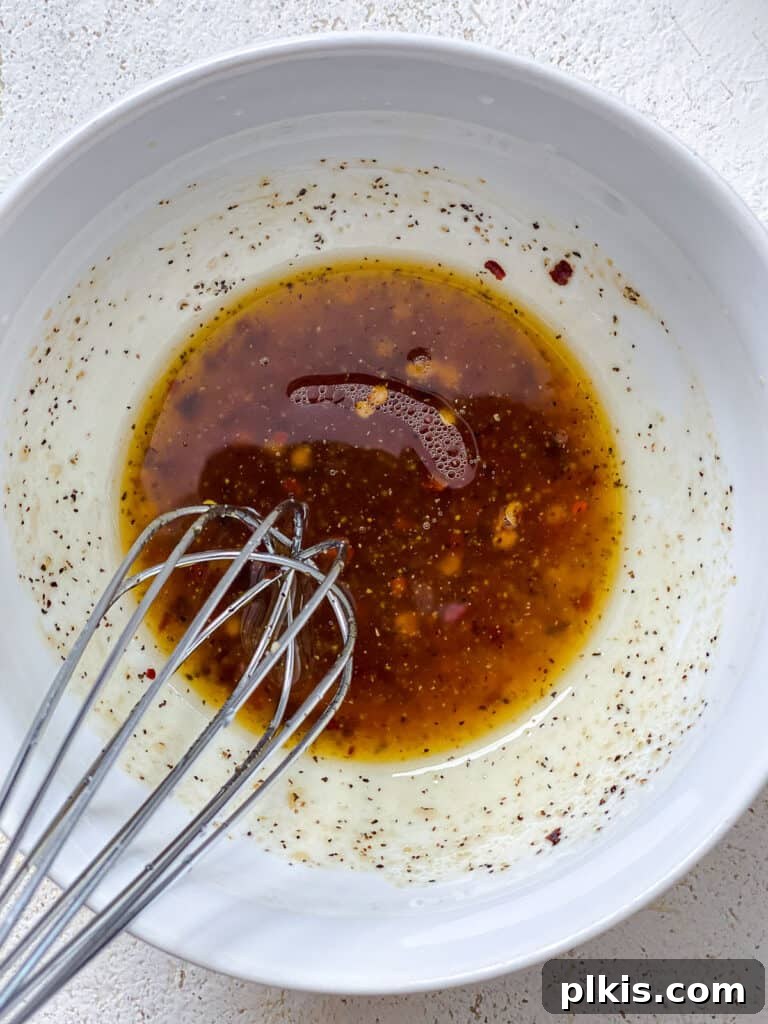 Vibrant Carrot Salad 7 process shot of whisking dressing in white bowl