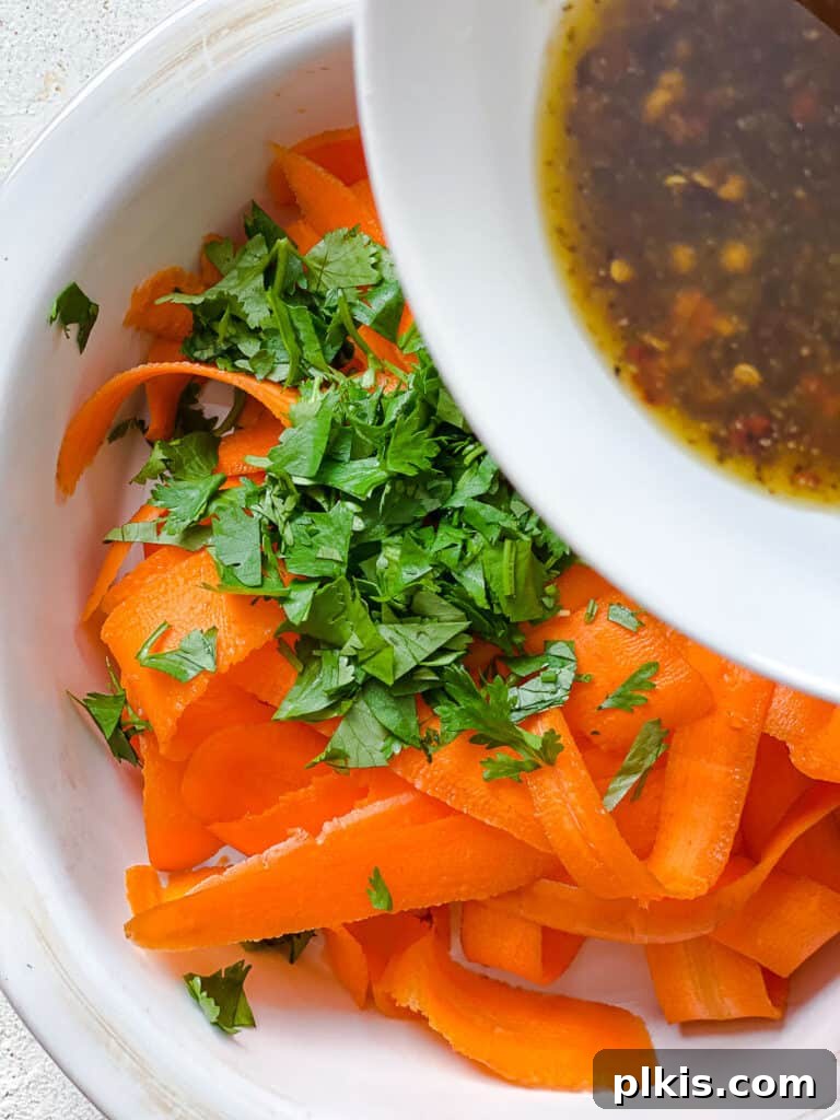 Vibrant Carrot Salad 8 process shot of adding dressing to bowl of peeled carrots