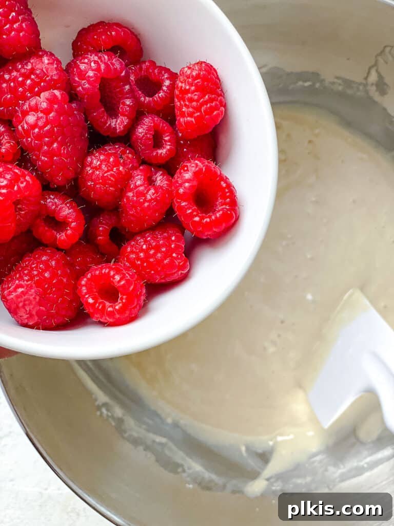 Simple Raspberry Cupcakes Your Way 5 process shot of adding raspberries to cupcake batter