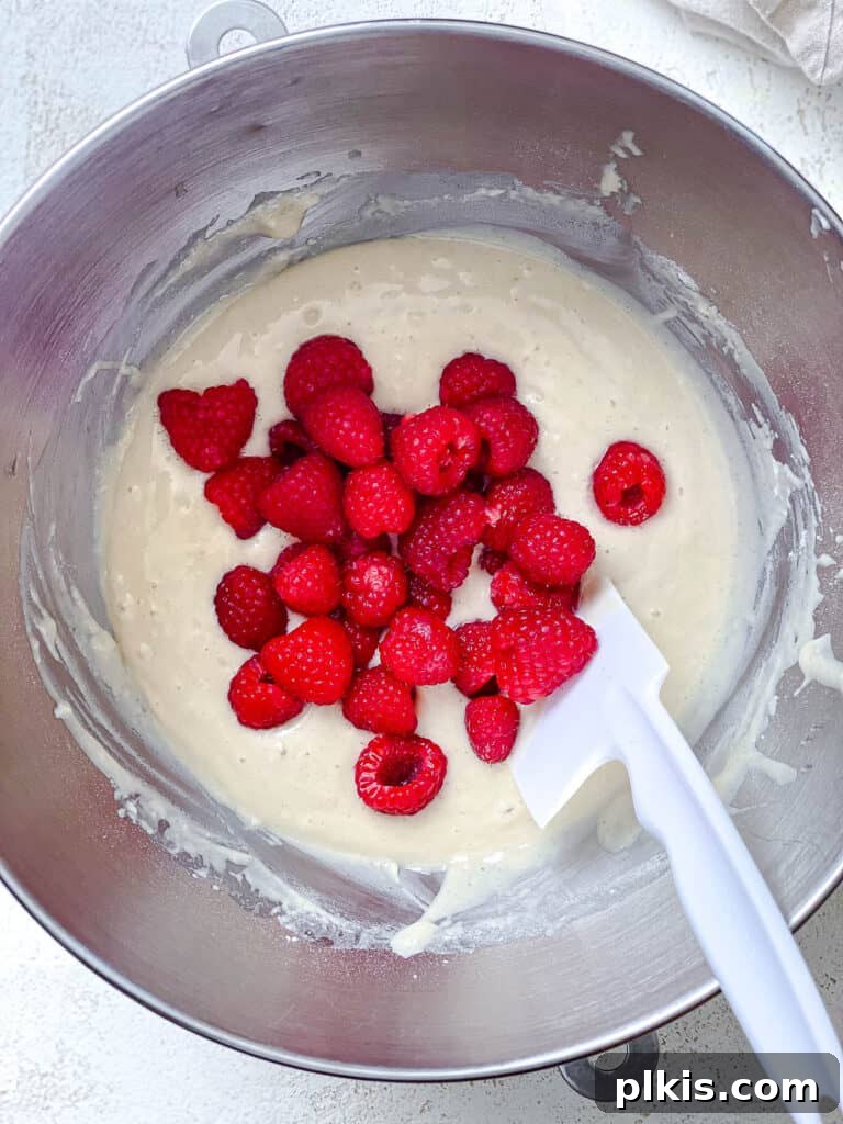 Simple Raspberry Cupcakes Your Way 6 process shot of stirring raspberries into cupcake mixture