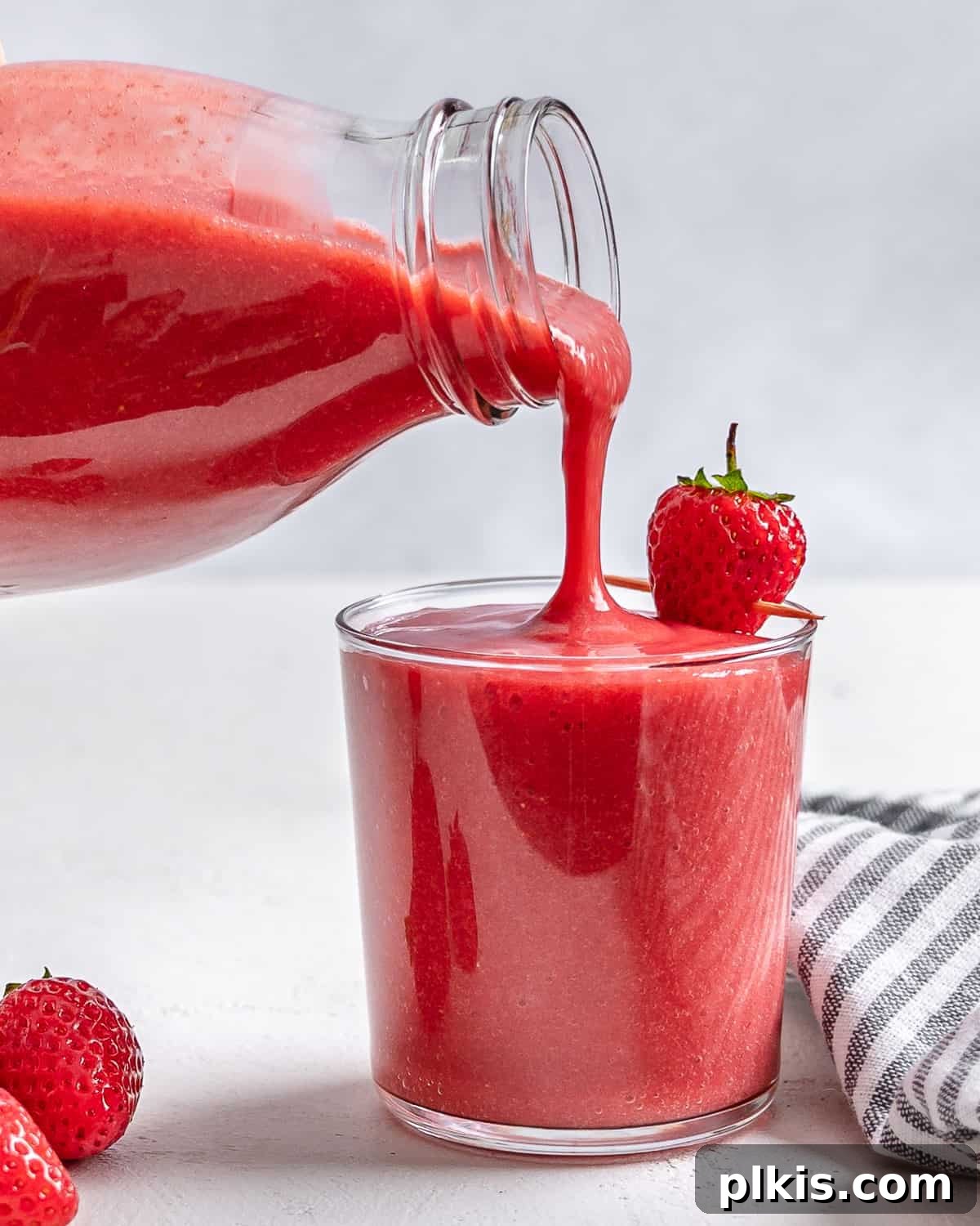 Refreshing Strawberry Juice Recipe 2 A glass of freshly made strawberry juice, garnished with whole strawberries, invitingly placed against a clean white background. Perfect for a refreshing summer drink.