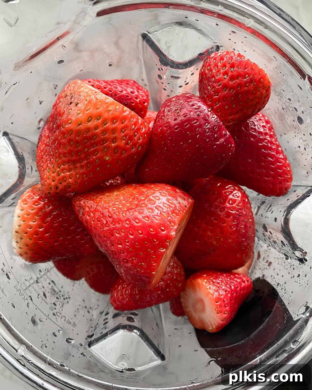 Refreshing Strawberry Juice Recipe 4 Fresh, vibrant red strawberries being blended into a smooth puree in a high-speed blender, illustrating a key step in making homemade strawberry juice.