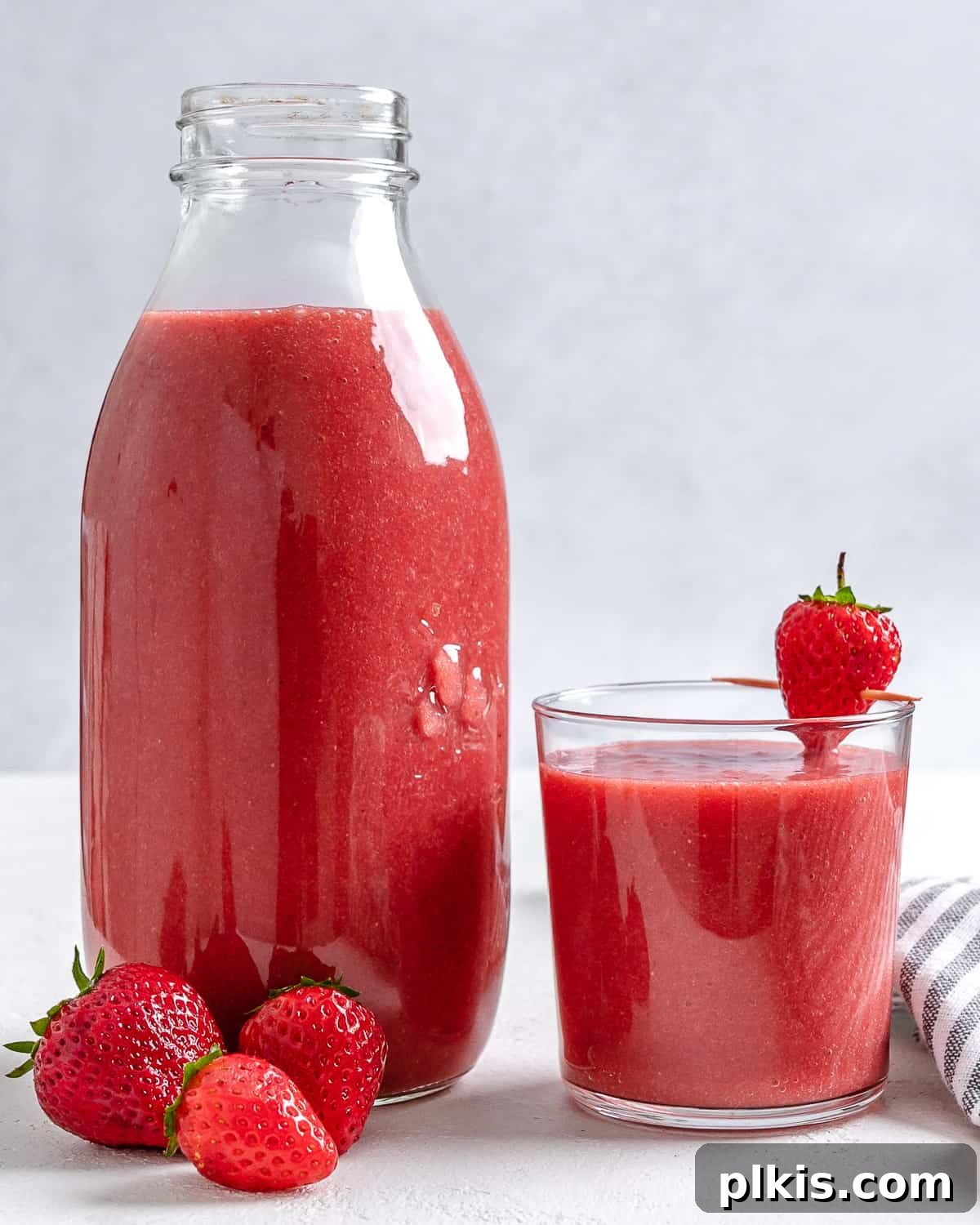 Refreshing Strawberry Juice Recipe 5 A beautifully presented jar of freshly prepared strawberry juice next to a filled glass, ready for serving, against a pristine white background. Highlighting the final, delicious result of the recipe.
