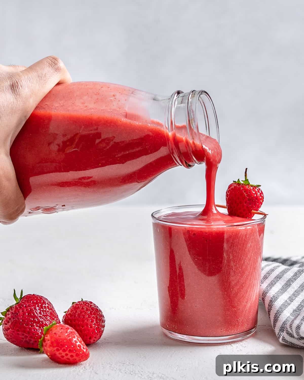 Refreshing Strawberry Juice Recipe 6 The final captivating image of a glass of strawberry juice, with fresh strawberries scattered nearby, embodying the perfect blend of taste and health, against a clean white backdrop.