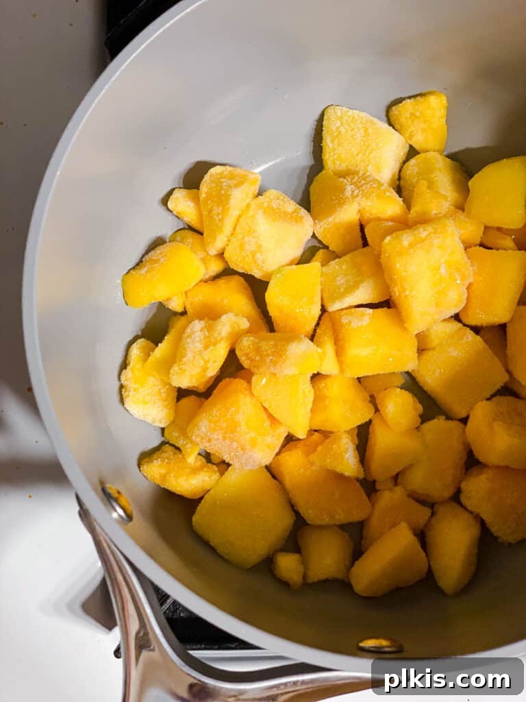 Versatile 3-Ingredient Mango Topping 4 Fresh mango chunks in a pot, ready for cooking, capturing the initial stage of compote preparation.