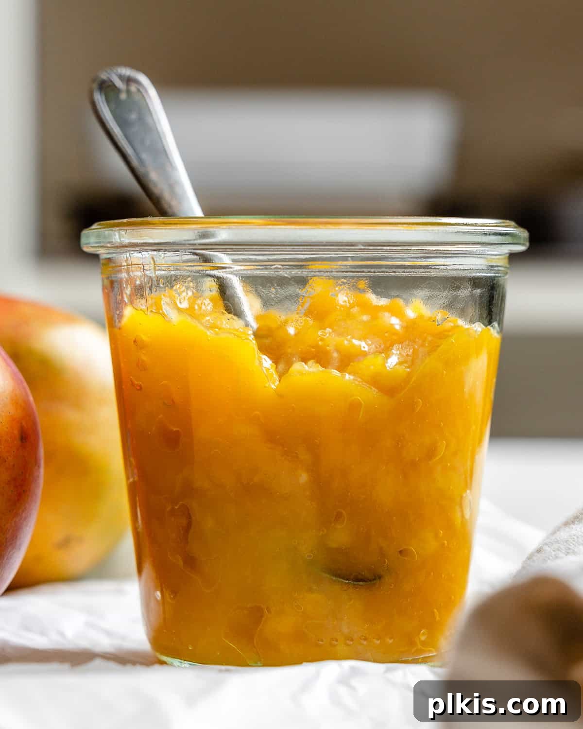 Versatile 3-Ingredient Mango Topping 10 A beautifully presented jar of homemade mango compote, highlighting its vibrant color and luscious texture, against a subtle, light background.