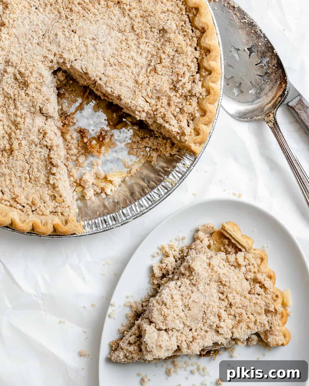 Zucchini Apple Pie Surprise 2 Completed Vegan Zucchini Mock Apple Pie with a slice plated on a white plate against a light background, showcasing its golden crumb topping and tender filling.