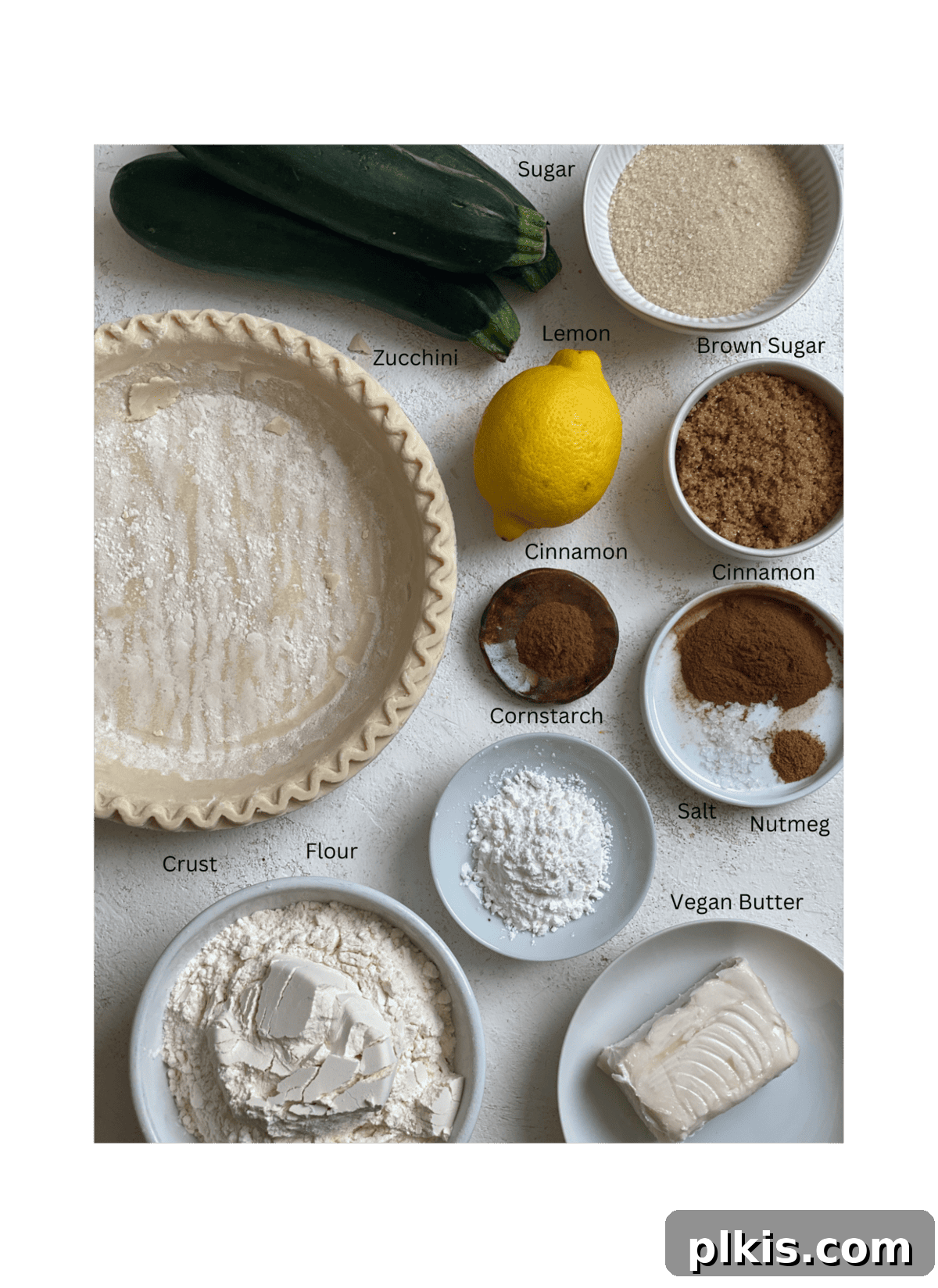 Zucchini Apple Pie Surprise 3 Ingredients for Vegan Zucchini Mock Apple Pie laid out on a clean white surface, highlighting fresh zucchini, sugars, spices, and a pie crust.