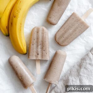 completed Healthy Banana Popsicles against a white surface alongside bananas
