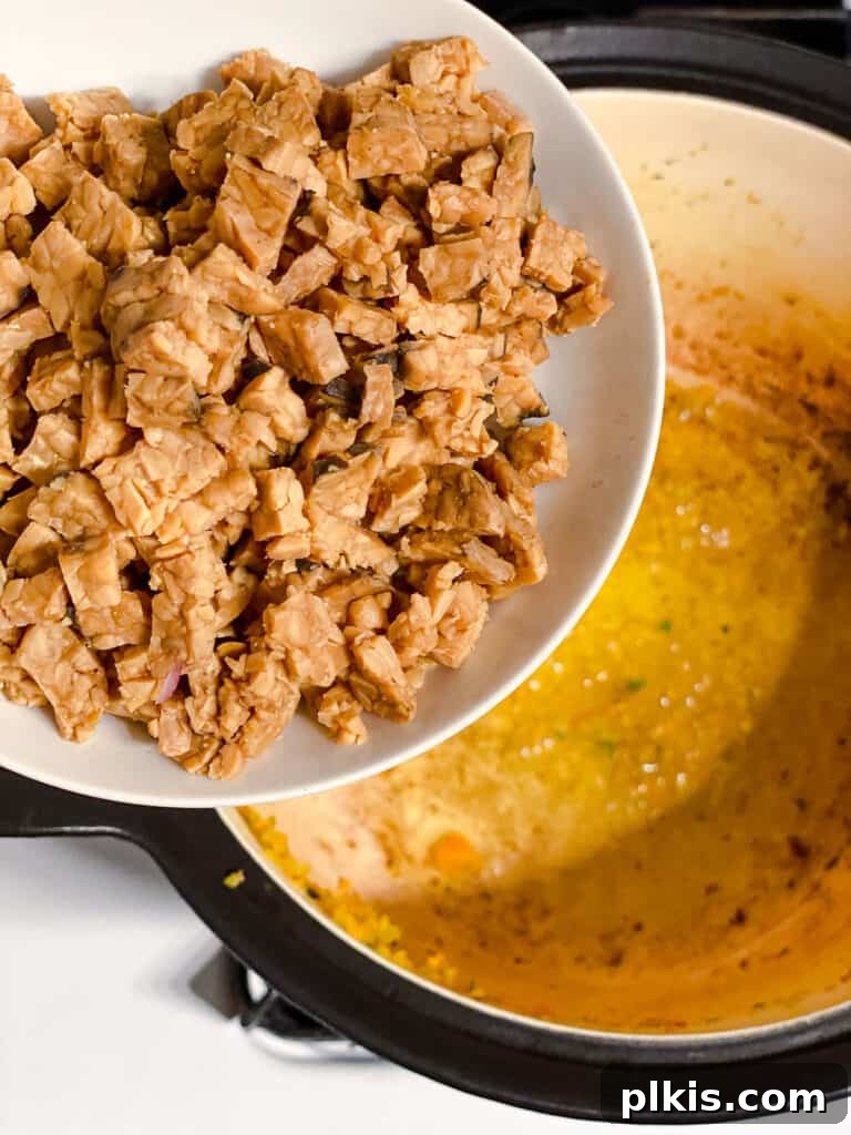 Hearty Vegan Ragu 8 Process shot of crumbled tempeh being added to the pot for browning, alongside the tofu.