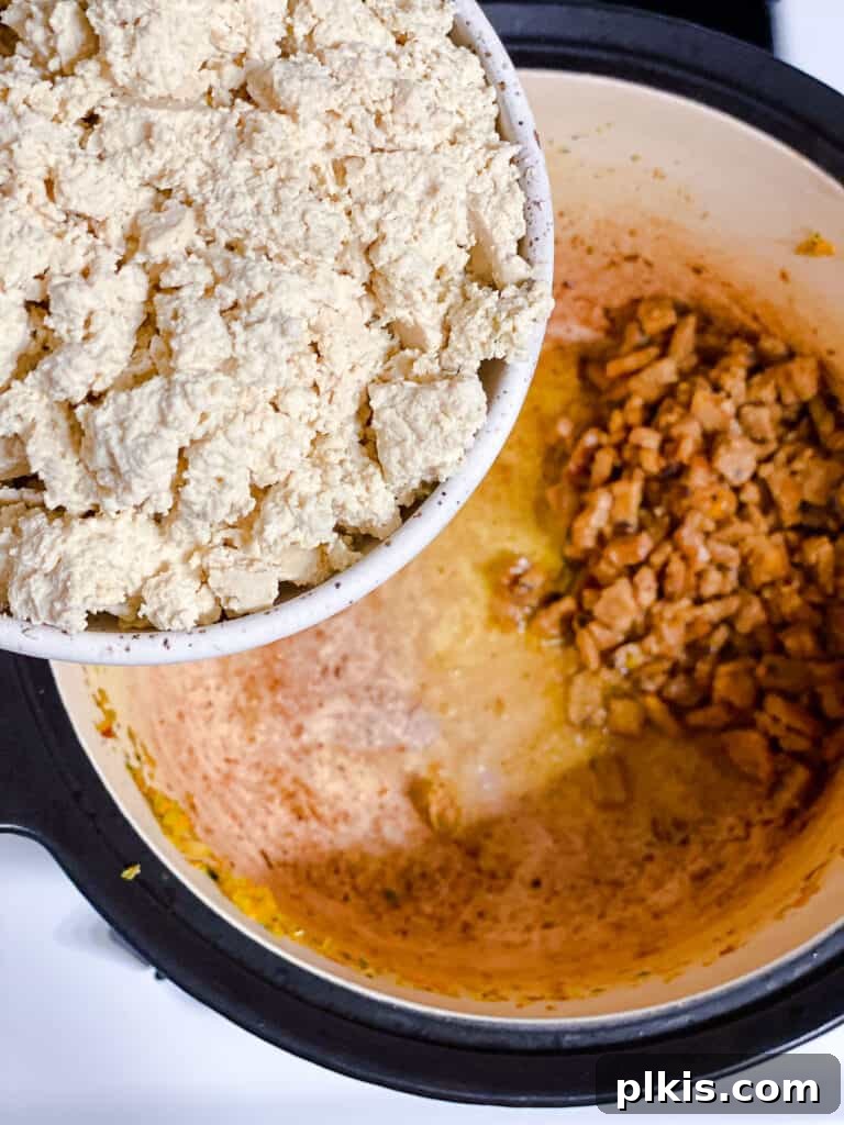 Hearty Vegan Ragu 10 Process shot of crumbled tofu being added to the pot for cooking and browning.