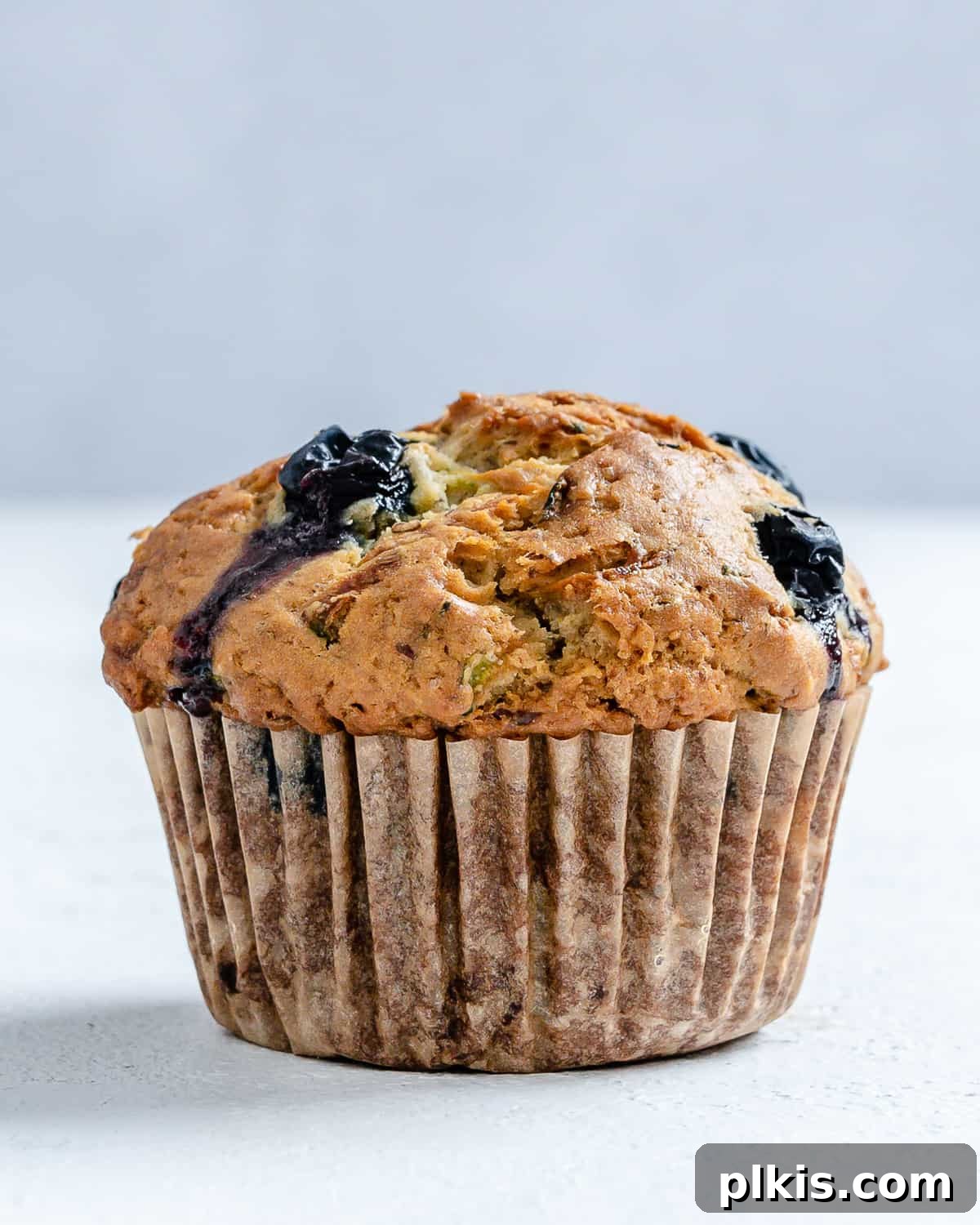 Garden-Fresh Vegan Blueberry Zucchini Muffins 8 Completed Blueberry Zucchini Muffin against a white background.