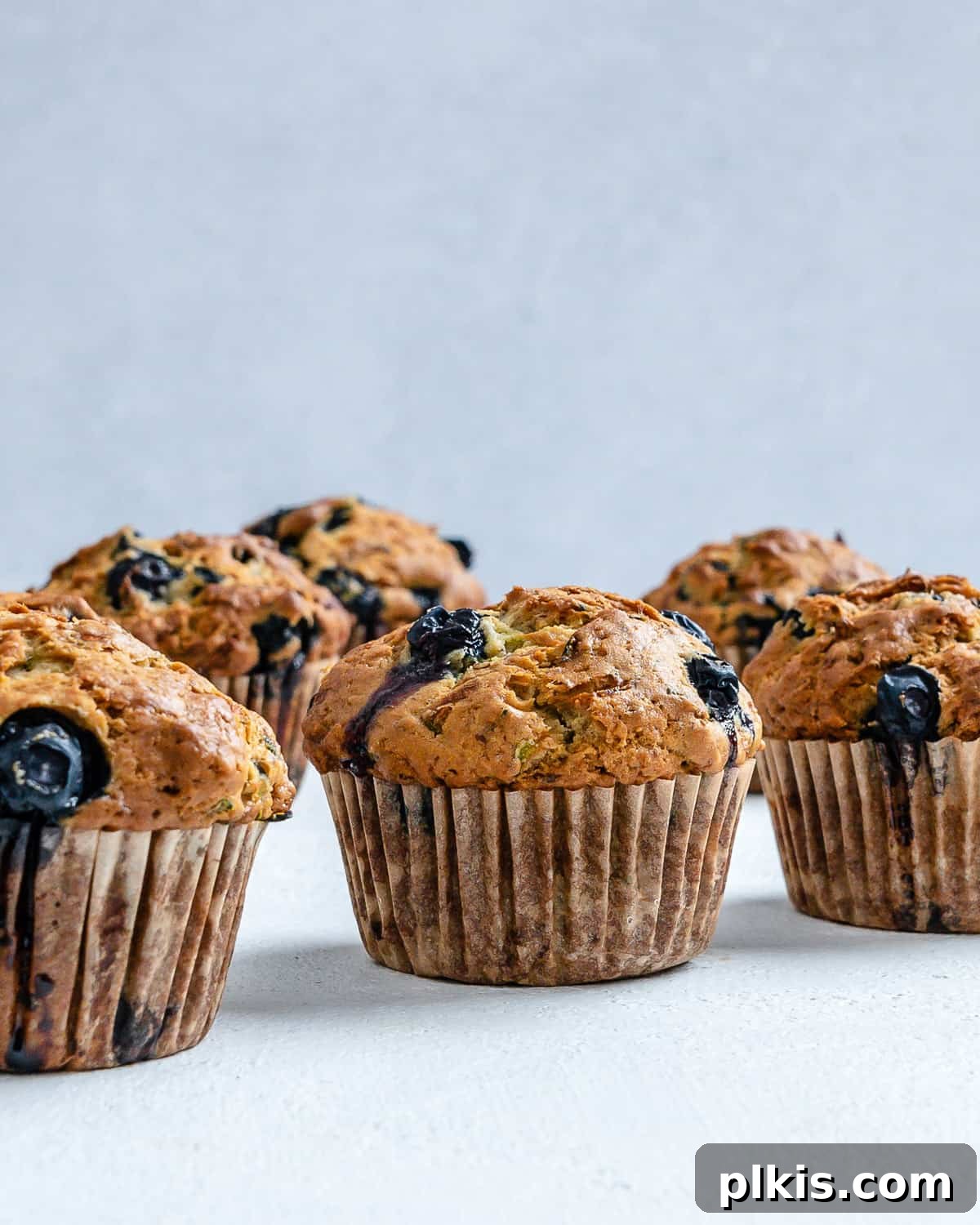 Garden-Fresh Vegan Blueberry Zucchini Muffins 9 Completed Blueberry Zucchini Muffins against a white background.