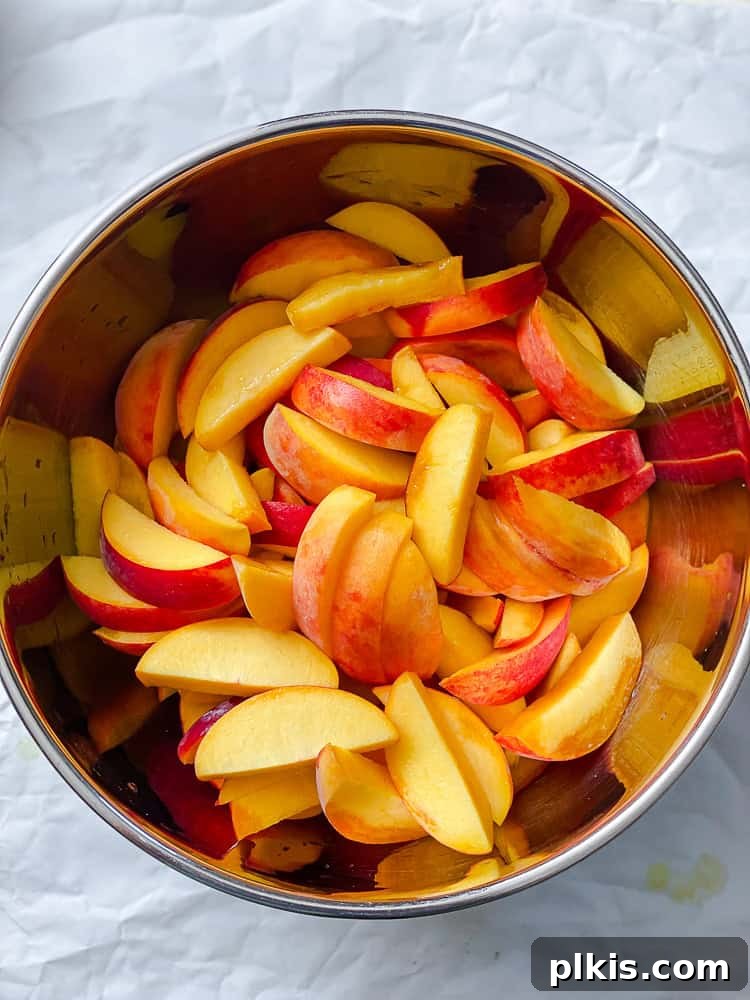 Effortless Vegan Peach Cobbler 4 Process shot showing sliced peaches in a large mixing bowl, ready for the filling ingredients.
