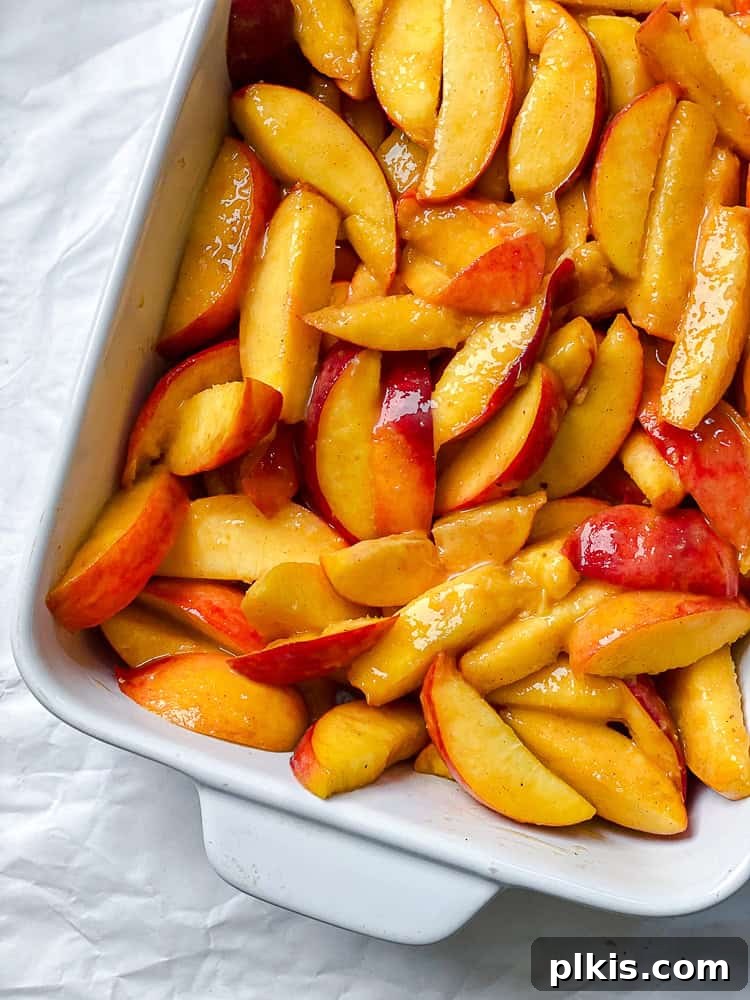 Effortless Vegan Peach Cobbler 6 Process shot showing the seasoned peach slices spread evenly in a glass baking dish.