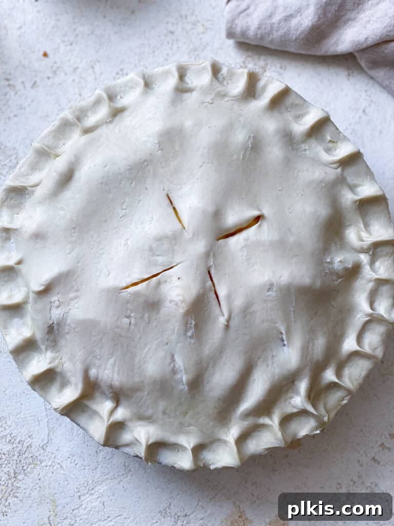 Golden Peach Mango Delights 7 A process shot showing the second pie crust being placed over the fruit filling, ready for sealing and baking.