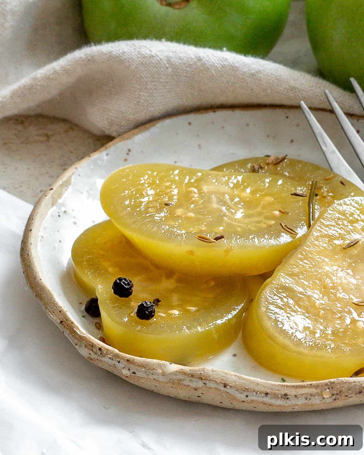 Tangy Green Tomatoes in a Flash 7 A perfectly portioned serving of quick pickled green tomatoes elegantly arranged on a pristine white plate, ready to be enjoyed as a refreshing side or condiment.