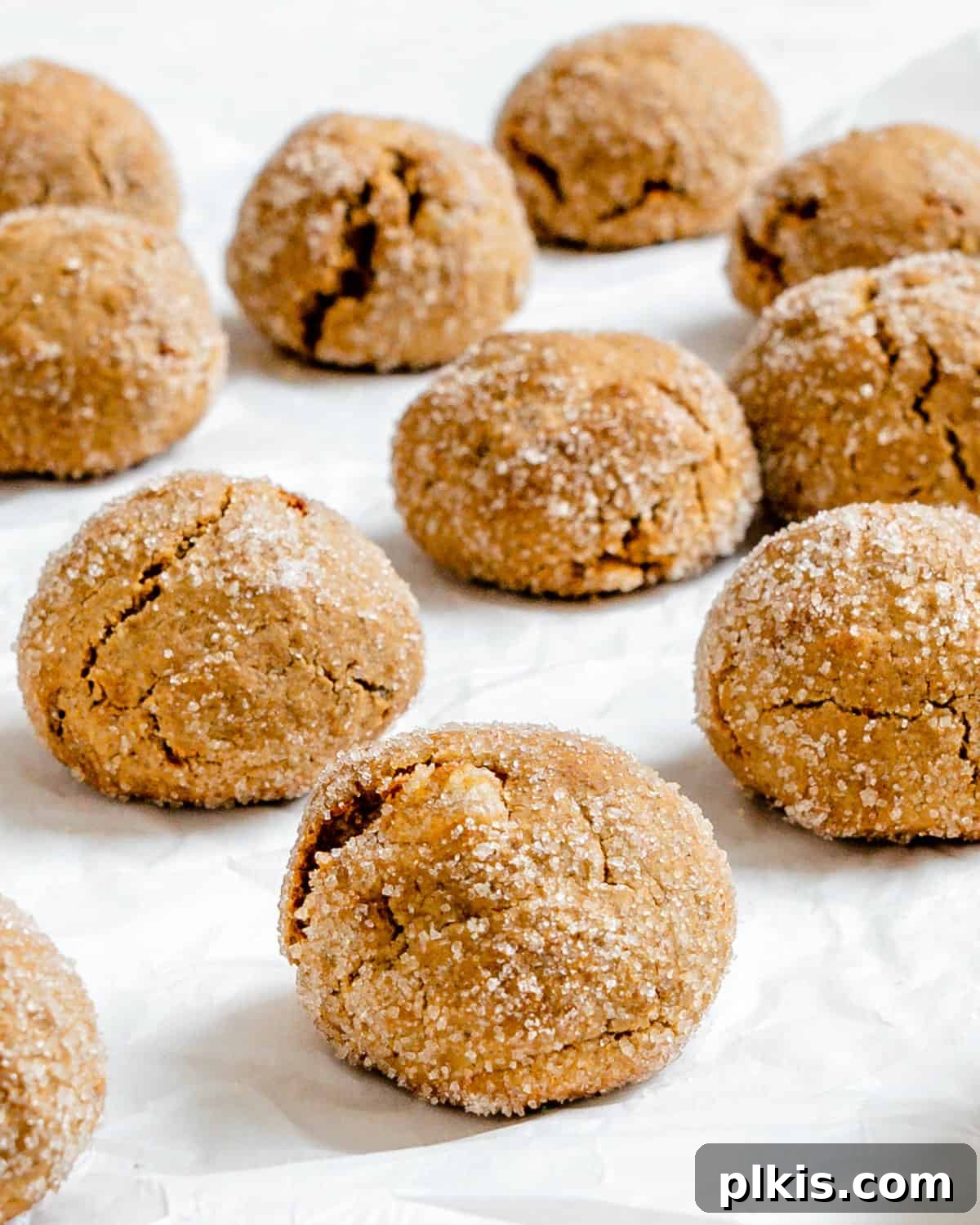 Bold Triple Ginger Vegan Snaps 2 Several golden-brown Triple Ginger Vegan Gingersnaps on a white surface, showcasing their crackled tops and inviting texture.