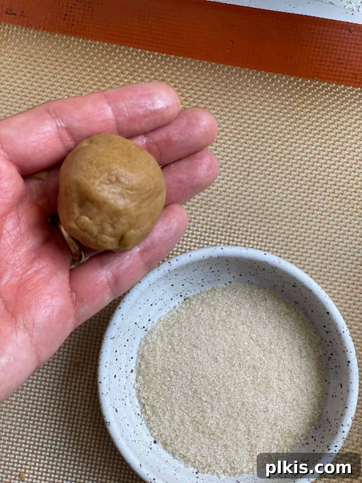 Bold Triple Ginger Vegan Snaps 12 Close-up of a perfectly rolled cookie dough ball next to a bowl of granulated sugar.