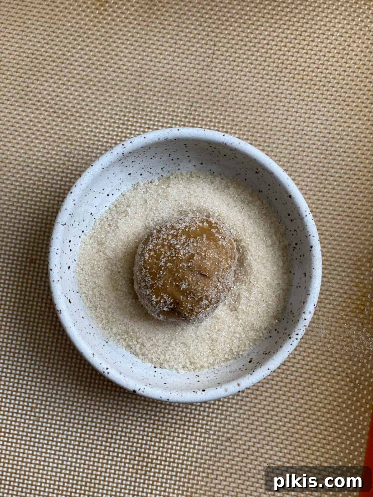 Bold Triple Ginger Vegan Snaps 14 Process shot displaying a cookie dough ball fully coated in sugar inside a bowl.