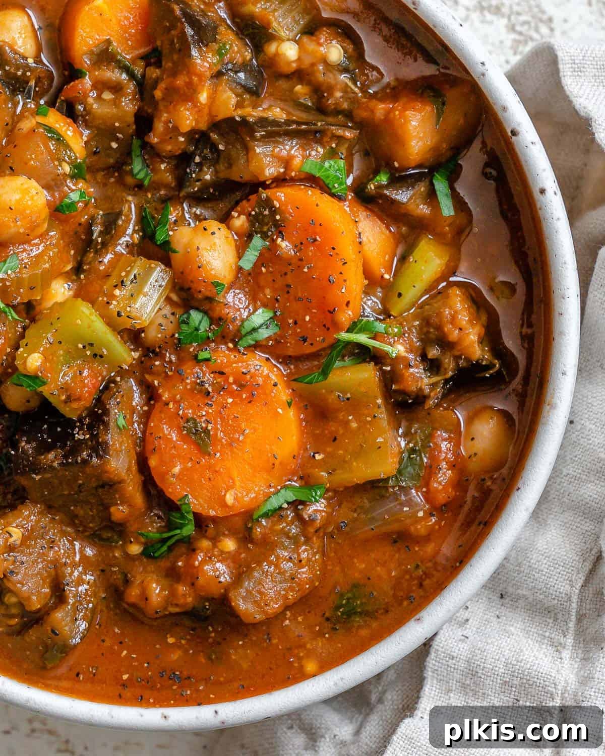Hearty Eggplant, Tomato, and Chickpea Stew 17 A close-up shot of the completed Eggplant Stew with Tomatoes and Chickpeas, showcasing its rich texture and vibrant colors, served in a bowl on a white surface.