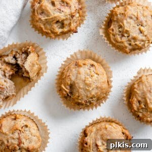 Several completed Vegan Apple Muffins spread out on a white surface.