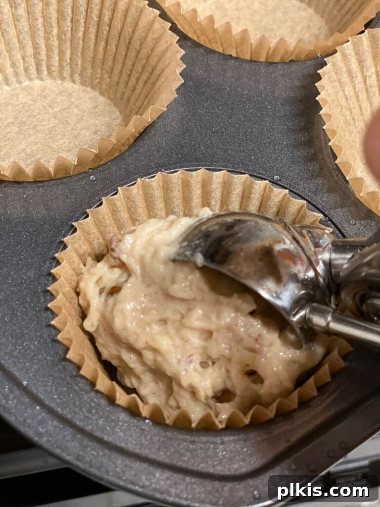 Wholesome Vegan Apple Muffins 9 Process of adding apple muffin mixture to baking cupcake liners in a muffin tray, ready for the oven.