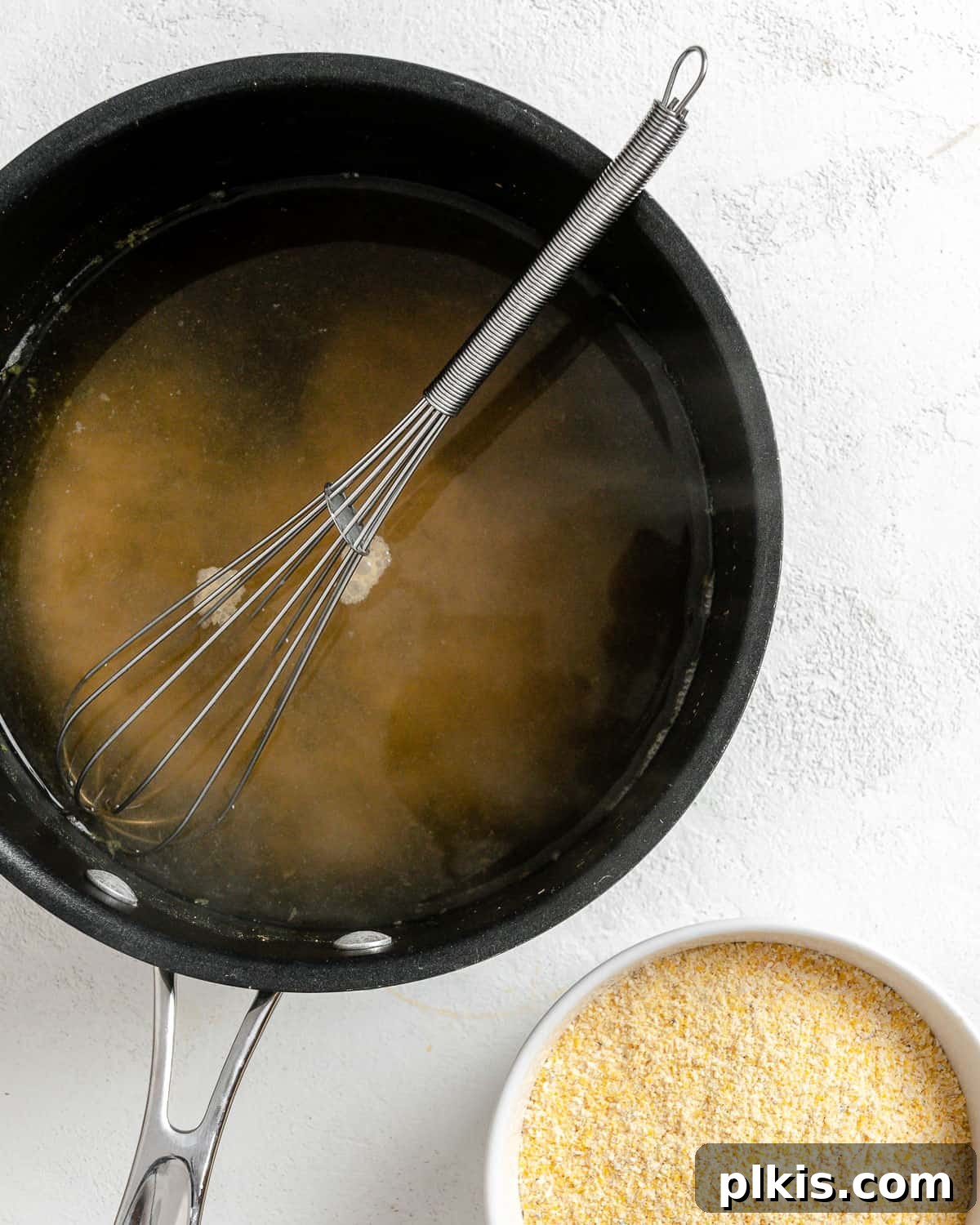 Golden Polenta Spinach Bake 14 A process shot showing cornmeal being slowly whisked into boiling water in a pot, ensuring a smooth polenta mixture.