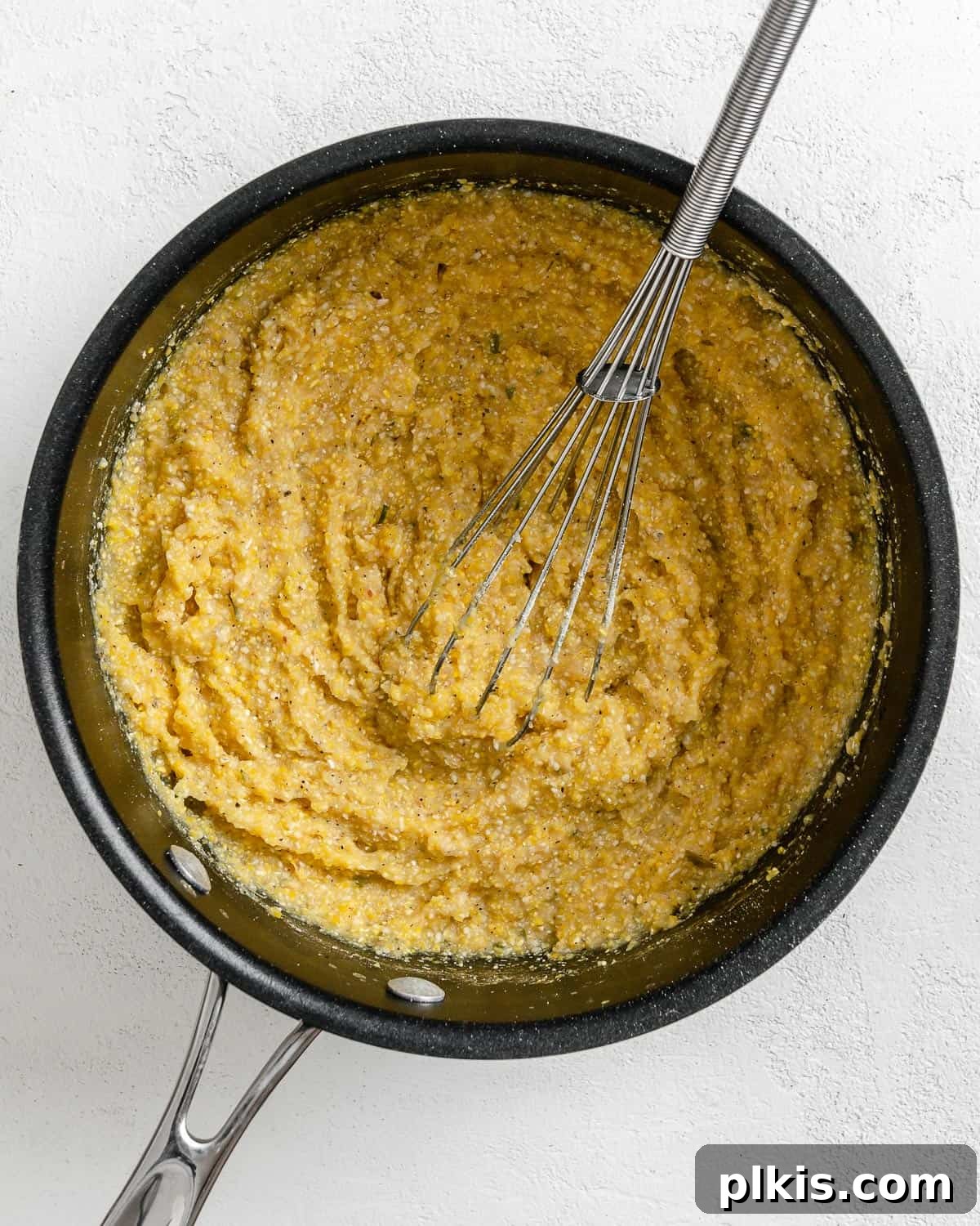 Golden Polenta Spinach Bake 15 A process shot of vigorously mixing thickening polenta in a pot with a wooden spoon, ensuring it cooks evenly without lumps.