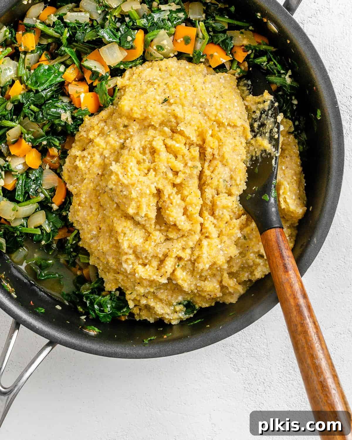 Golden Polenta Spinach Bake 16 A process shot of adding the cooked vegetable and spinach mixture into the pot of creamy polenta, ready to be combined.