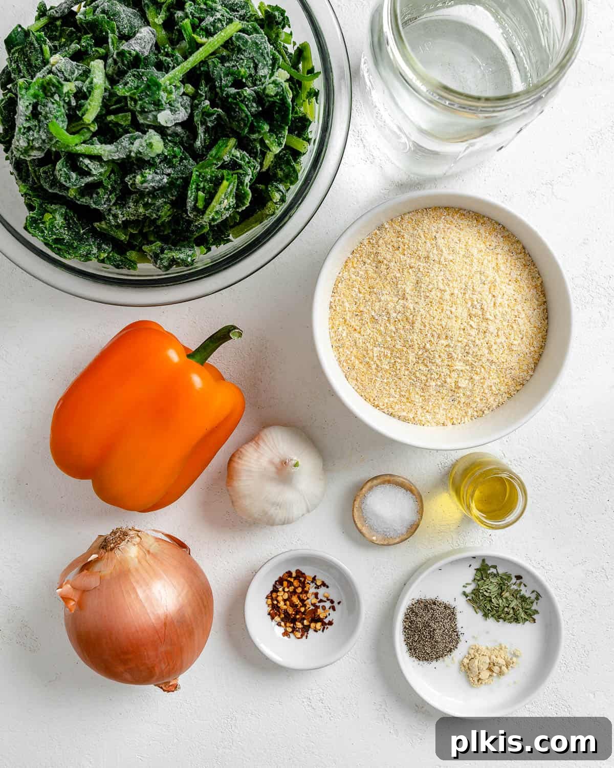 Golden Polenta Spinach Bake 3 A selection of measured ingredients for Garlicky Spinach and Pepper Polenta Pie, including onions, garlic, bell peppers, and thawed spinach, arranged against a clean white background.