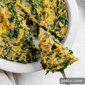 Golden Polenta Spinach Bake 21 A completed Garlicky Spinach and Pepper Polenta Pie with a slice being pulled away from the main dish, revealing the vibrant filling.