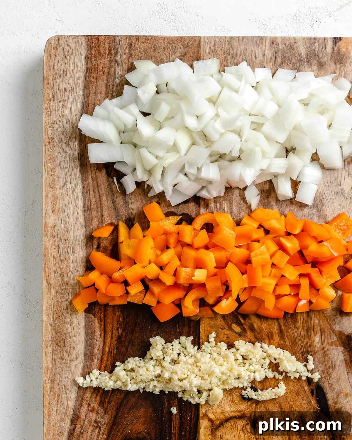 Golden Polenta Spinach Bake 5 Finely minced onions, diced orange bell peppers, and crushed garlic cloves neatly arranged on a cutting board, ready for sautéing.