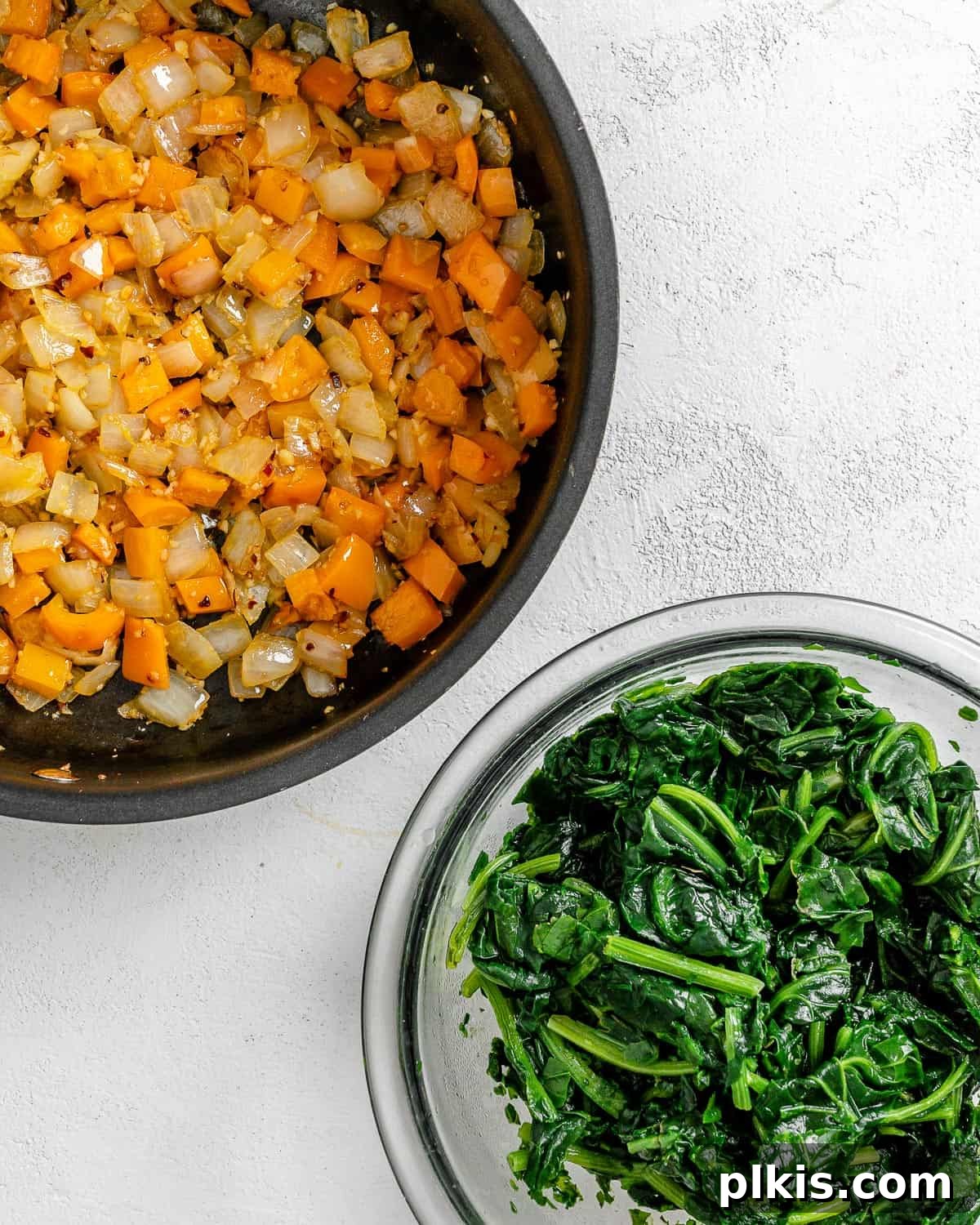 Golden Polenta Spinach Bake 10 Cooked onions, garlic, and bell peppers in a black pan, with a bowl of thawed spinach beside it, ready to be added.