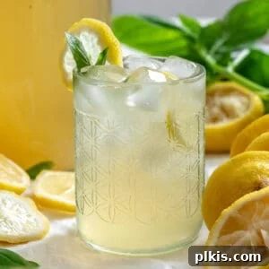 completed Basil Lemonade in a glass with ingredients in the background