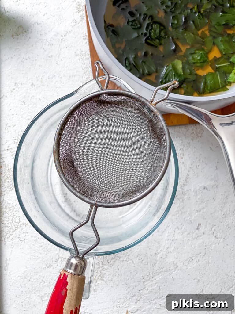 Basil Lemonade Creative Infusions 10 Process shot of straining the basil simple syrup into a pitcher.