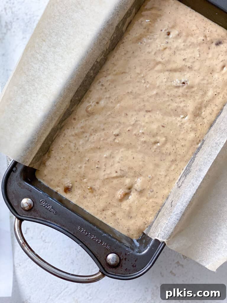 Moist Coffee Walnut Loaf 7 A process shot showing the vegan coffee and walnut loaf cake batter being poured into a greased loaf pan, ready for baking.