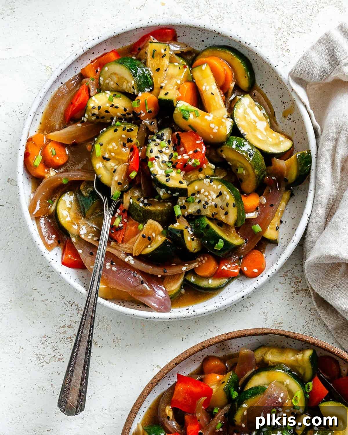 Speedy Zucchini Stir-Fry 2 Two bowls of delicious and easy zucchini stir-fry, garnished with sesame seeds and green onions.