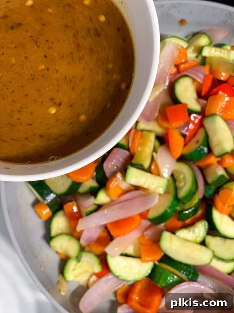 Speedy Zucchini Stir-Fry 8 Stir-fry sauce being poured over cooking vegetables in a hot pan, ready to thicken and coat.