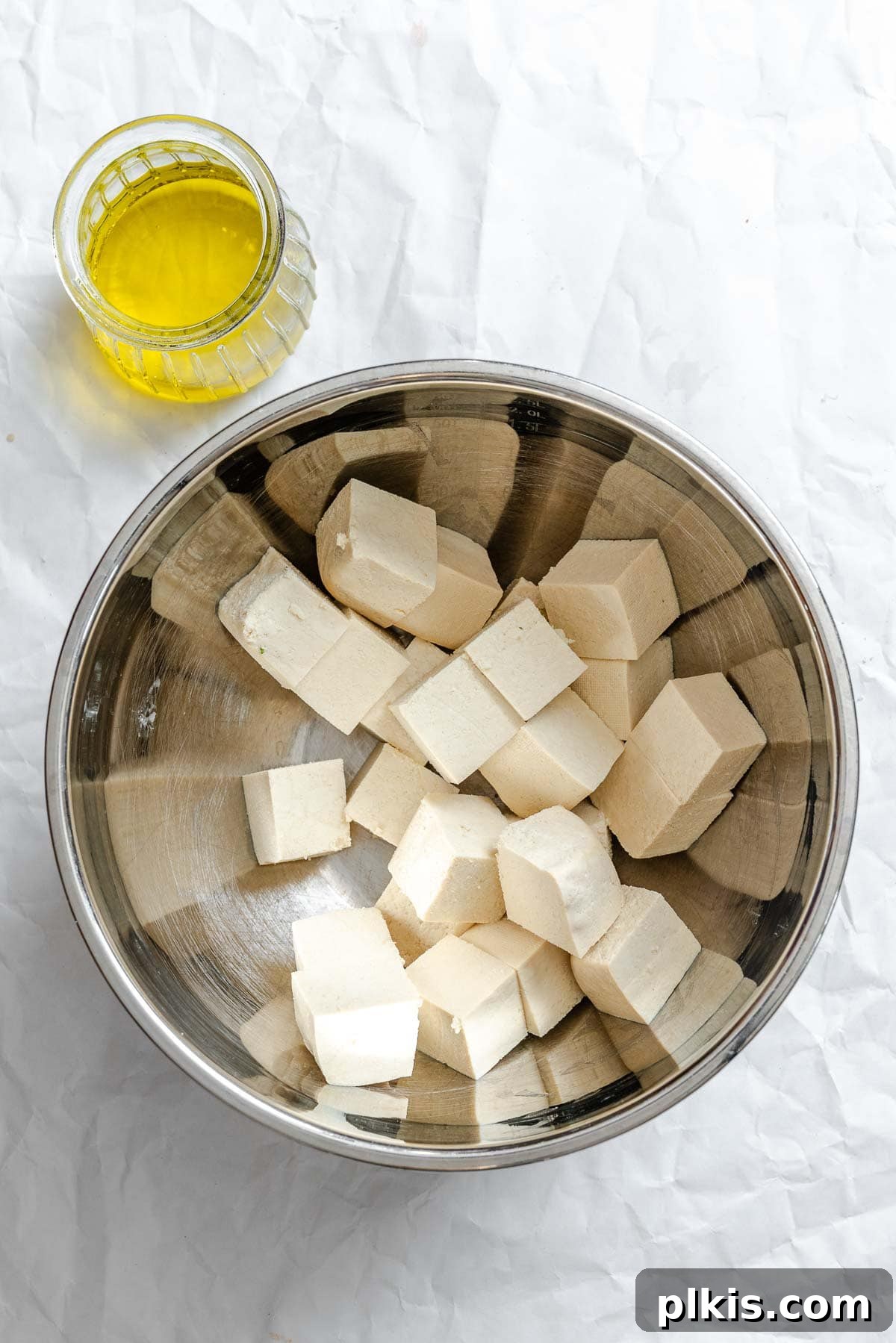 Golden Crispy Tofu with Rich Peanut Sauce 4 Process shot showing tofu in a bowl alongside oil on a white surface.
