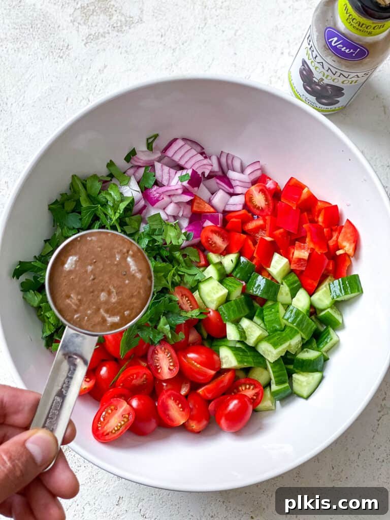 Vibrant Garden Couscous Salad 11 Adding balsamic vinaigrette dressing to a bowl of fresh vegetables.