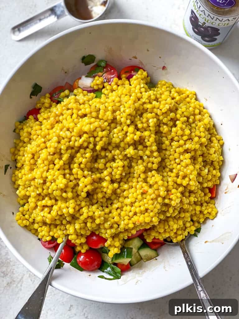 Vibrant Garden Couscous Salad 14 Adding cooked couscous to a bowl of mixed fresh vegetables and dressing.