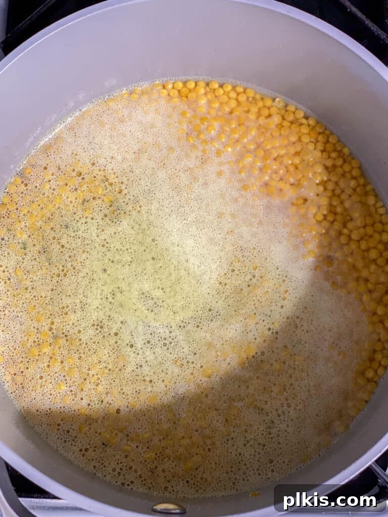 Vibrant Garden Couscous Salad 5 Process shot of pearl couscous cooking in vegetable broth in a pot.