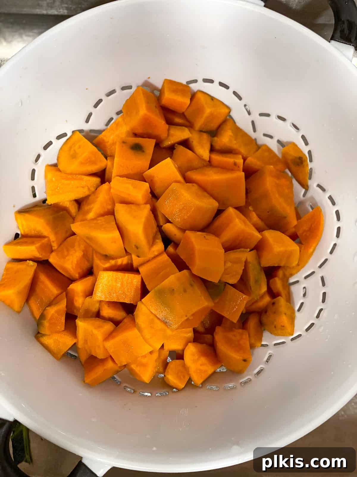 Velvety Vegan Sweet Potato Mash 6 Cooked sweet potatoes draining in a white colander, showing their vibrant orange color.