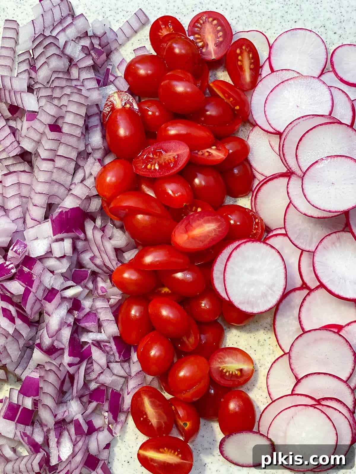 Vegan Fiesta Bowl 5 A selection of freshly diced red onion, halved cherry tomatoes, and thinly sliced radishes, neatly arranged and ready for the salad.